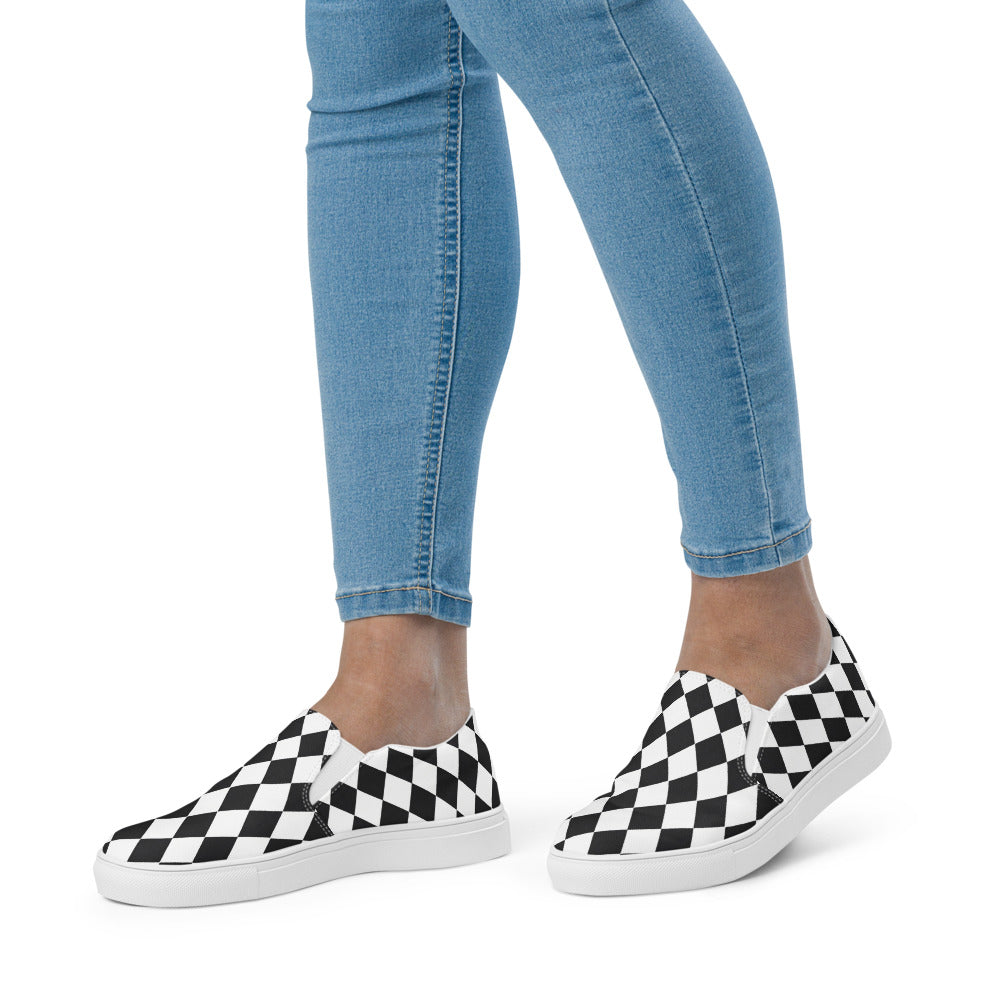 Plaid slip-on shoes worn with blue jeans on a white background